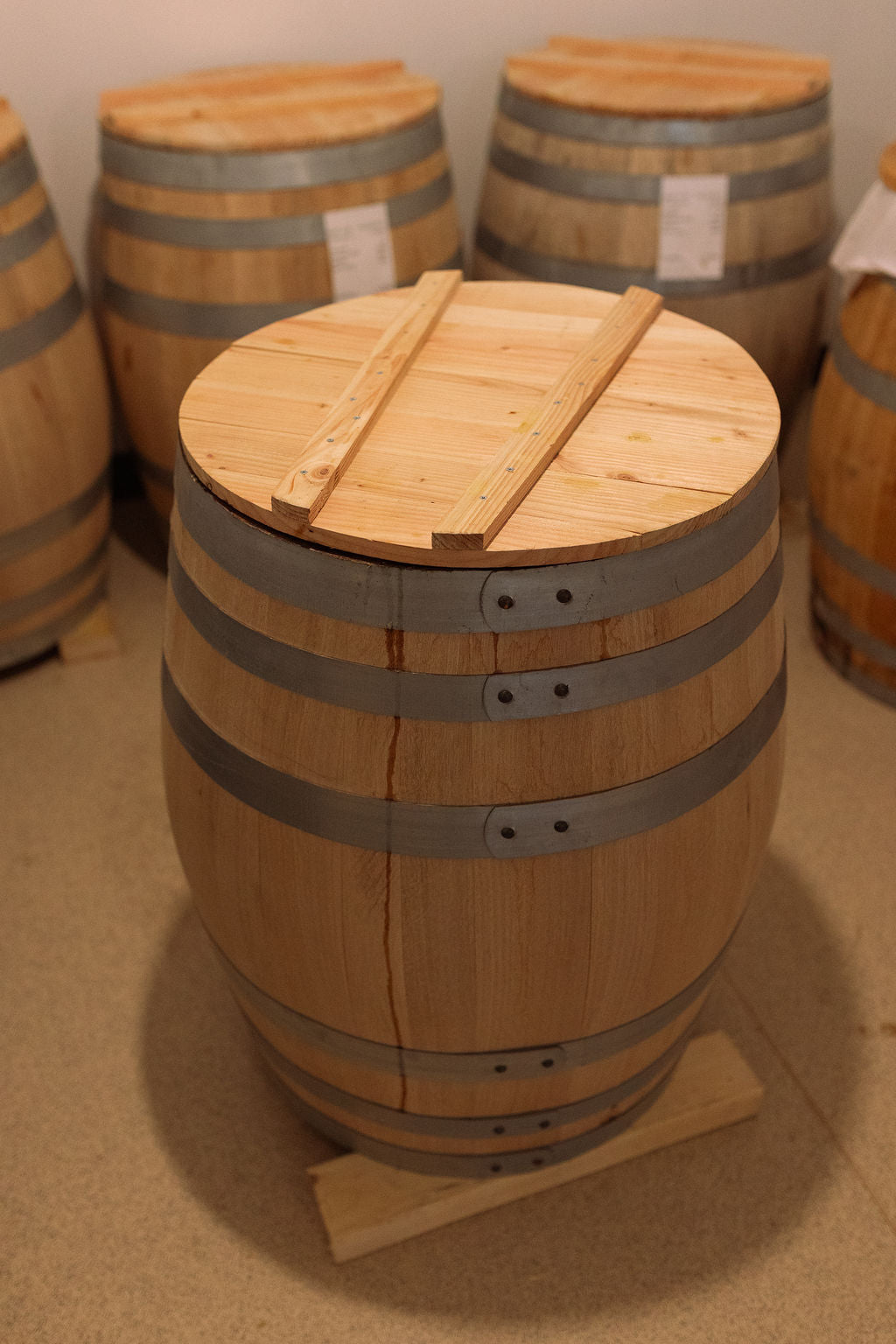 A wooden barrel lid resting on a fermentation barrel, left to work undisturbed.